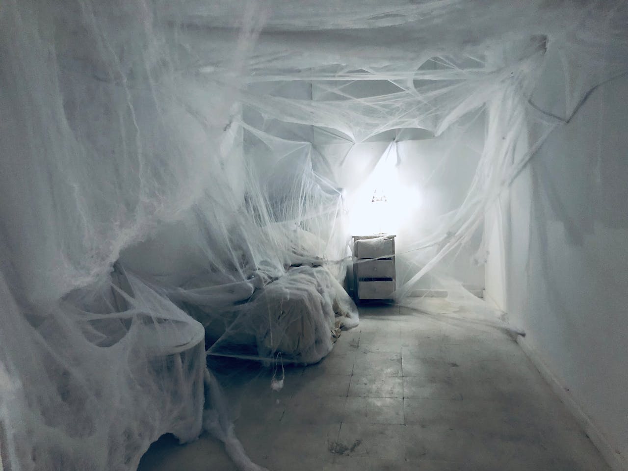 A spooky, cobweb-filled bedroom with dim lighting, evoking an eerie atmosphere. Perfect for Halloween themes.